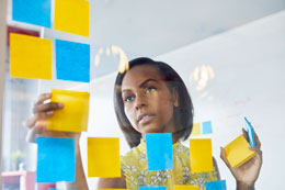 Woman planning with post-it notes along the glass wall.