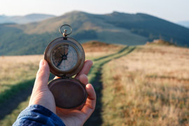 Person holding a compass, looking down a path through the grass. Our Pathways to Online Learning course is available now.